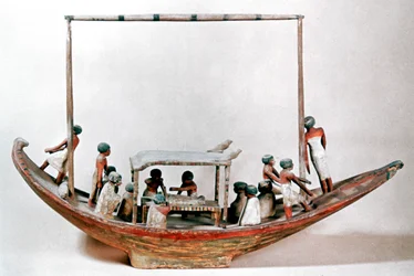 Gammel egyptisk modell av en båt som frakter en mumie til graven