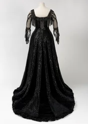 Svart ankellang aftenkjole båret av dronning Alexandra, med perle- og paljettdekor og med dronning Alexandras karakteristiske sorte silkebånd med navn i gullbokstaver, laget av Barolet of Knightsbridge, London, 1908-1910