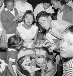 SKUESPILLEREN OG FASHIONMODELLEN ELSA MARTINELLI VED DEN XVIII INTERNASJONALE FILMFESTIVALEN PÅ VENEZIA LIDO (hun skriver autografer til unge fans. På bordet står en flaske Schweppes) - 1957