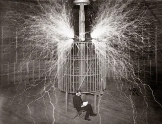 Nikola Tesla sitting in his Colorado Springs laboratory with his “Magnifying Transmitter”