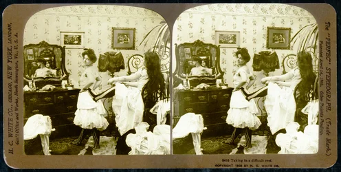 Stereoskopisk kort som viser en kvinne som snøres inn i et korsett, ca. 1900 (sepia-bilde) (se også 473244)