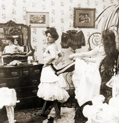 Stereoskopisk kort som viser en kvinne som snøres inn i et korsett, ca. 1900 (sepia-bilde) (se også 473243)