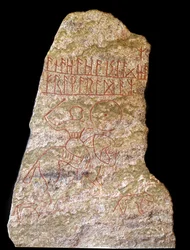 En stele med runeinnskrifter som representerer en vikingrytter med en hund (stein)