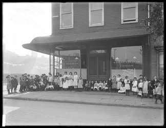 Barn poserer foran en uidentifisert butikkfilial til Queens Borough Public Library, New York, ca. 1910