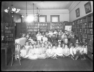 Gruppeportrett av barn på lesesalen til en uidentifisert gren av Queens Borough Public Library, ca. 1910