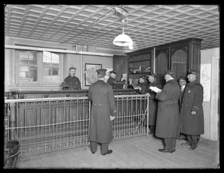 Interiør av uidentifisert politistasjon, viser offiserer og resepsjon, ca. 1913-14