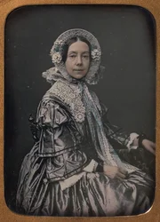 Sittende middelaldrende kvinne kledd i finesser, 1854-60.