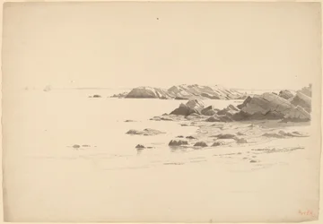 Rocklined strand med fjerne båter